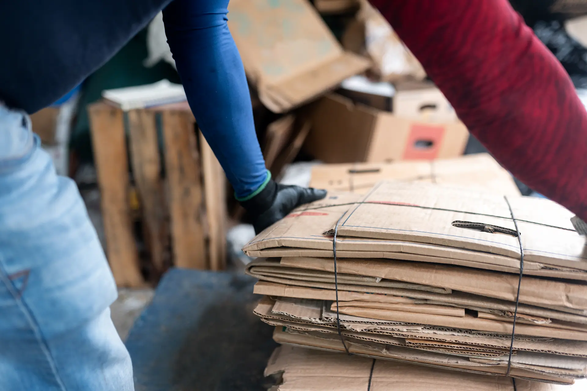 Workers handling flattened cardboard boxes during a residential junk removal service, focusing on furniture removal